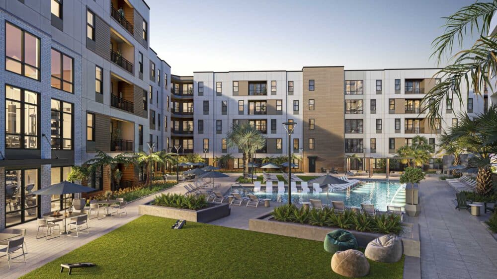 courtyard of midrise apartment building at sunset with swimming pool and tropical greenery